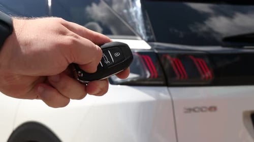 Fahrzeug kaufen. Mann benutzt Schlüssel in der Nähe eines neuen Autos im Freien, Nahaufnahme