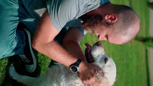 Man Pet Owner Plays with His Happy Pet Dog Golden Retriever Outside on Lawn Public Park During