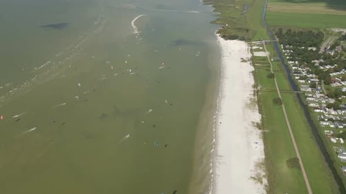 Aerial view of people doing kite surfing along the beach sunny day, Netherlands