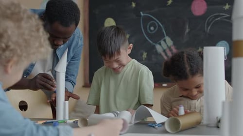 Elementary School Student Making Paper Rockets with Teacher