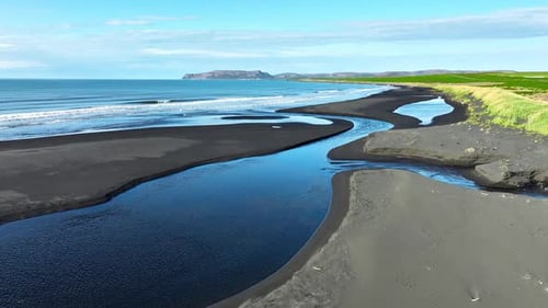 River Flows Into the Ocean on a Beautiful Coast in Iceland Landscape with Black Volcanic Sand in