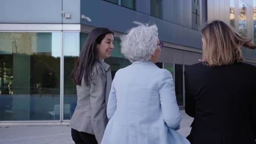 Three Businesswomen Walk and Talk Together Outside Their Office Building