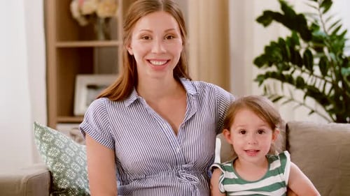 Smiling woman with child sitting on couch indoors