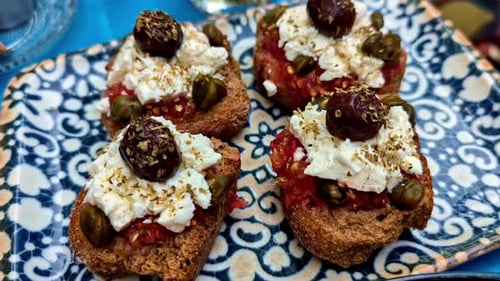 Greek toast with feta cheese, sundried tomatoes, and olives - close up detail