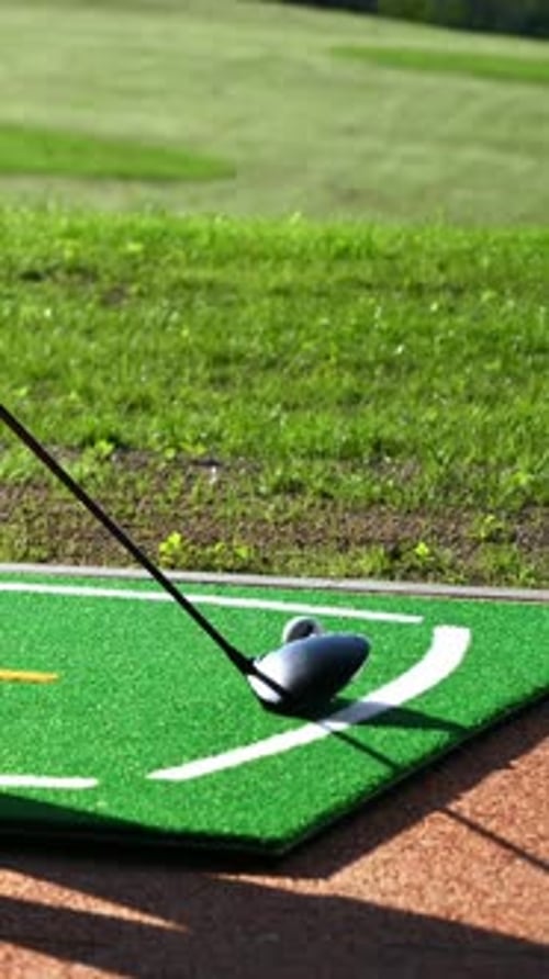 Close up of a golf club hitting a golf ball into a hole. Vertical