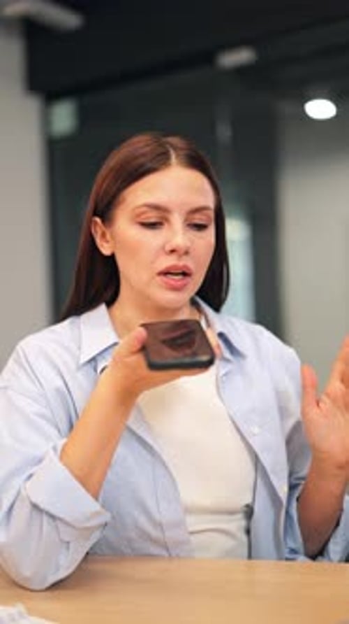 Focused Woman Dictating Voice Message on Smartphone in Office