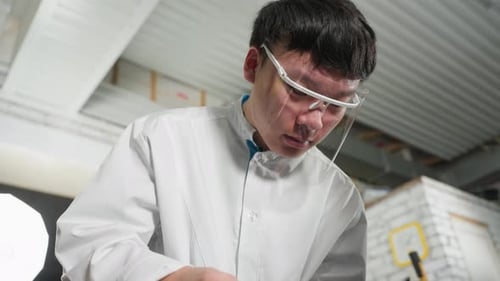 Gros plan d'un étudiant en blouse de laboratoire utilisant un pied à coulisse Vernier dans un atelier automobile