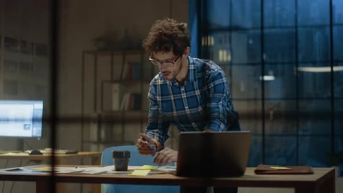 Junger kreativer Designer, der an seinem Schreibtisch arbeitet, sich auf den Papierkram konzentriert und das richtige Design auswählt,