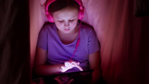 Girl Using Tablet with Headphones in Cozy Setting