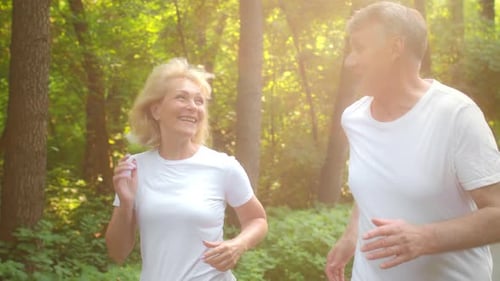 Active Senior Couple Enjoys Jogging Together in a Park During Morning