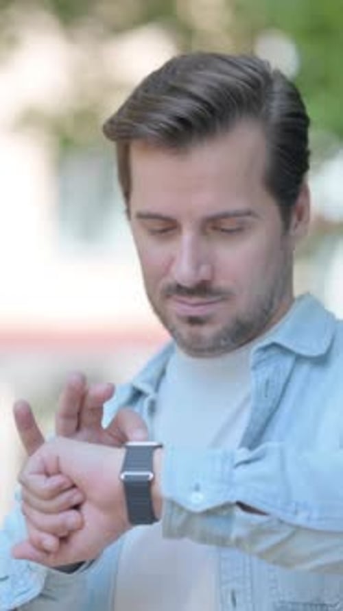 Man Interacts with Smartwatch Outdoors in Vertical Video