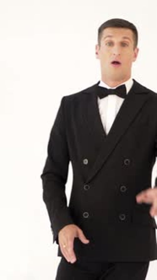 un showman con un elegante traje negro con pajarita está posando