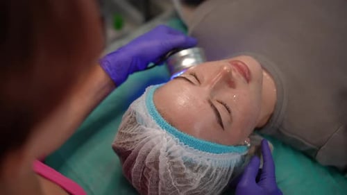 Beautician Performing Light Therapy Facial On Woman