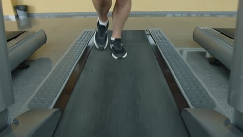 Closeup View of a Caucasian Woman Using a Treadmill for Running Workout