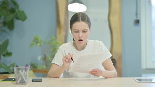 Casual Young Woman Upset while Reading Documents at Work