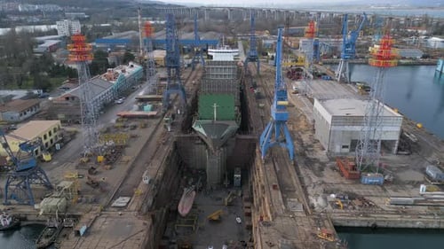 Luftaufnahme einer Schiffsreparaturwerft mit Trockendocks, Kränen und Frachtschiffen in einem Industriehafen
