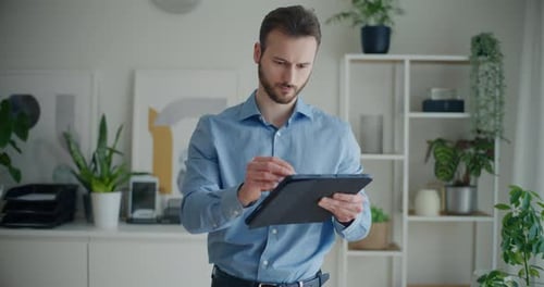 Young Adult Man Uses Tablet Indoors at Home