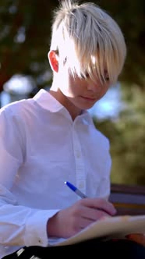 Young Student Writing and Studying Outdoors in Park