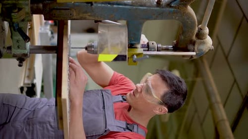 Man Drilling Wood in Workshop with Machine