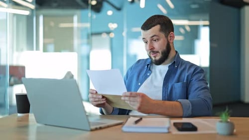 Happy Bearded Man Reads Letter at Office Desk