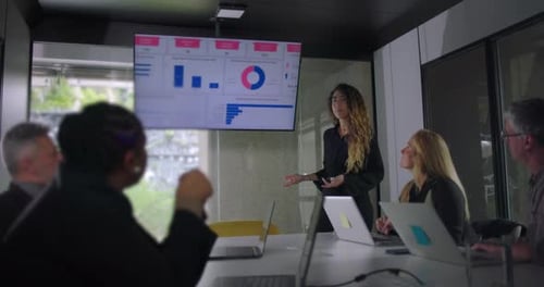 Woman Gives Business Presentation to Team in Office