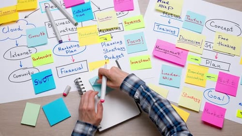 Hands of businesswoman writing down note using paper stickers. Top view of desktop. Post.