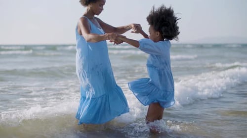 Mother and Daughter Playfully Twirl in Ocean