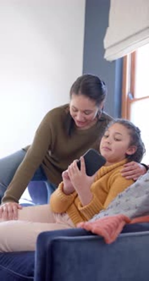 Adult and Child Look at Phone on Couch