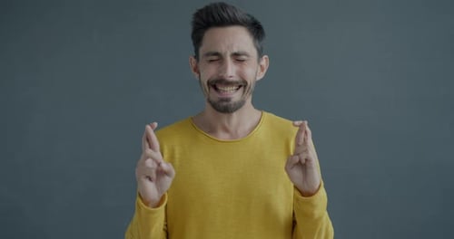 Slow Motion Portrait of Young Man Crossing Fingers Making Wish Praying Then Rubbing Hands and