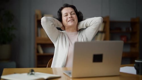 Adult Woman Sits in Home Office at Laptop Computer on Online Freelance Job Takes Break and Happily
