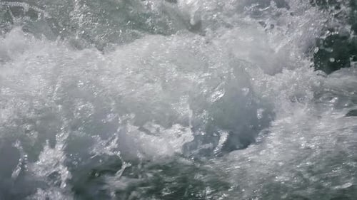 Splashes of Water in a Mountain River with a Fast Current Under the Bright Sun Slow Motion Closeup