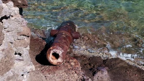 Old rusted cannon washed up on the shore of an island in the Caribbean