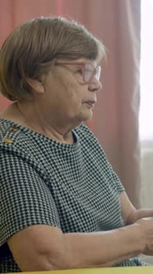 Senior Woman Sitting on a Sofa Using a Remote Control