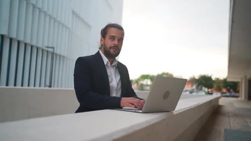 Homme d'affaires debout à l'extérieur avec ordinateur portable travaillant à distance Travail à distance à l'extérieur près du bureau