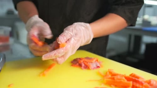 The hands of a professional sushi chef cut fresh red sea salmon fillet into thin slices