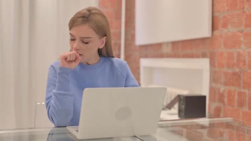 Woman Coughing While Working on Laptop at Home