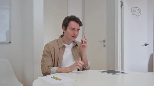 Young Adult Talking on Phone at Desk