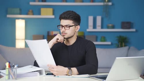 Man Studying Paperwork at Home Office Desk
