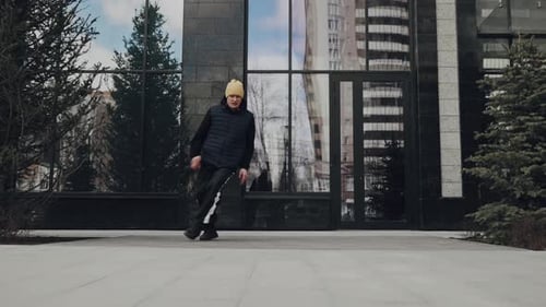 A Young Male Dancer in Streetwear Performing Breakdance Moves on an Outdoor Urban Stage with