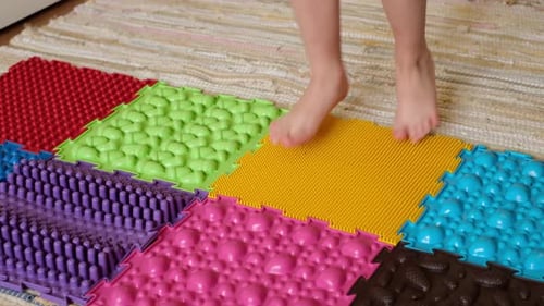 Child's Feet Walk on Colorful Textured Mats
