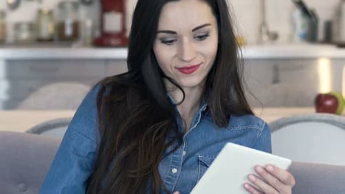 Woman Using Tablet and Smiling on the Couch
