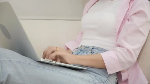 Woman working on laptop at home on sofa
