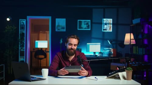 Man with Beard Holding Object in Dark Office