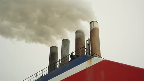 Smokestacks spew smoke into gray sky
