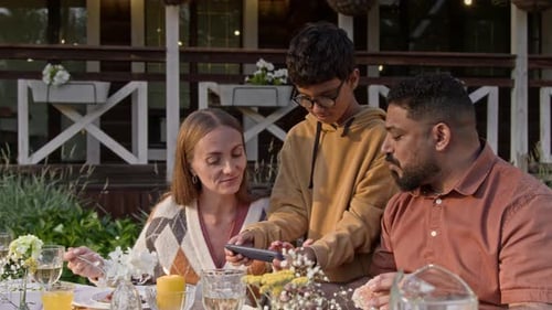 Family Uses Smartphone at Meal Outside Home
