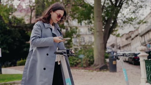 Woman Using Phone with Electric Scooter in City
