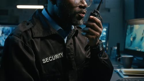 Security Guard Communicating on Walkie-Talkie in Monitoring Station