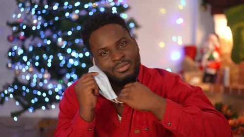 Retrato de um homem afro-americano positivo tirando a máscara facial Covid19 suspirando olhando para a câmera