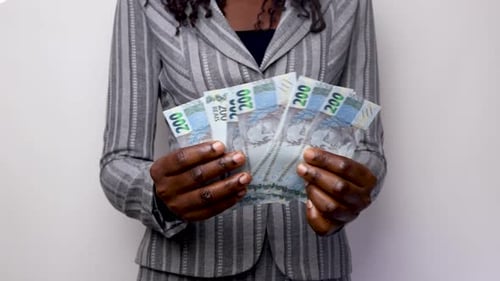 Person Counting Currency in Front of White Wall