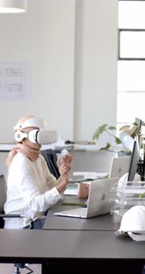 Vertical video: Using VR headset, woman interacting with virtual content in modern office